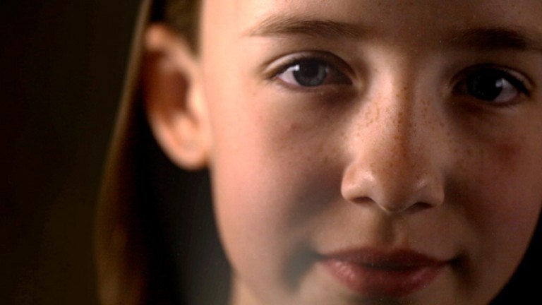 A photo of a young girls face, up close while looking at the camera.