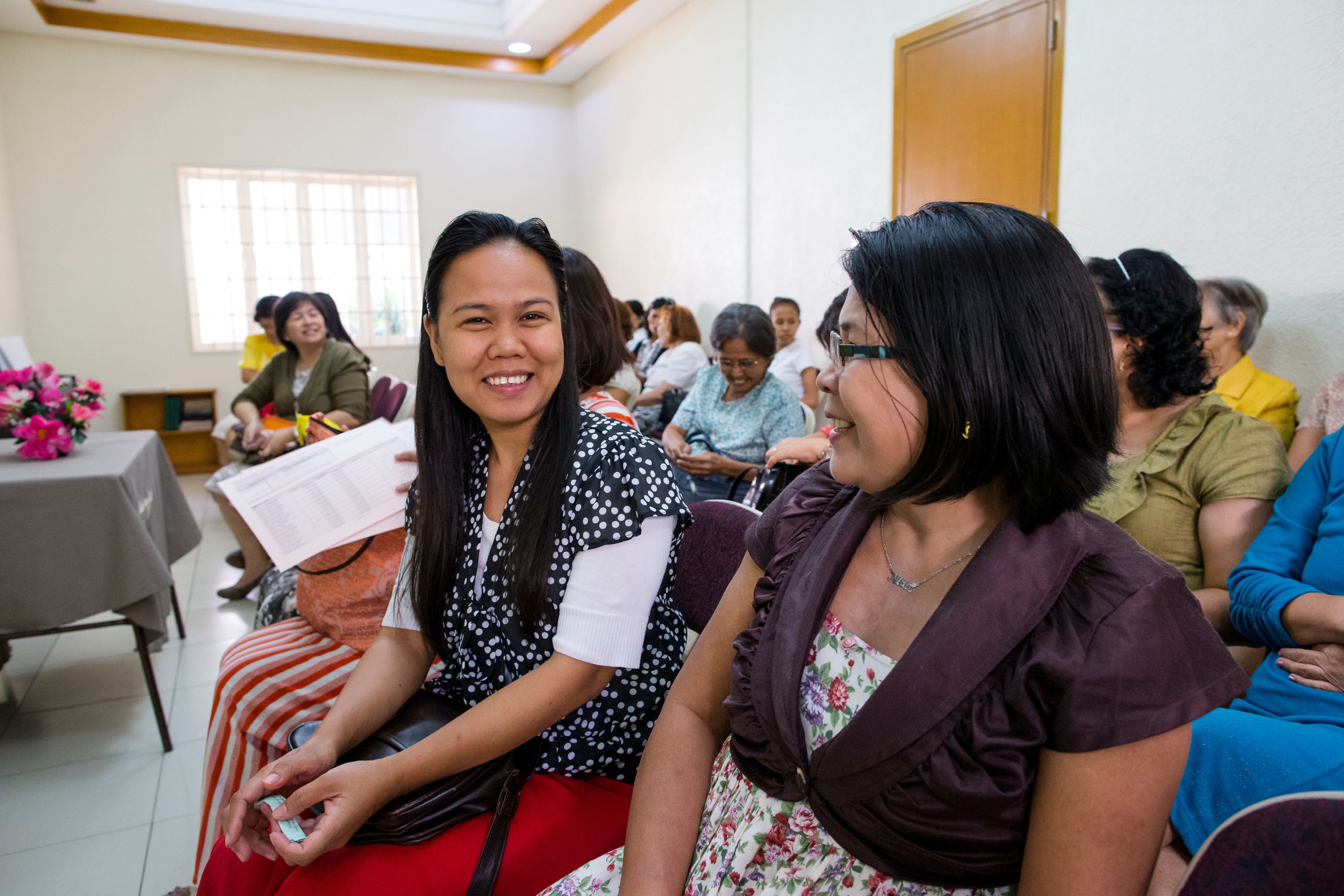 A group of Relief Society sisters in the Philippines talk together in their meetinghouse.