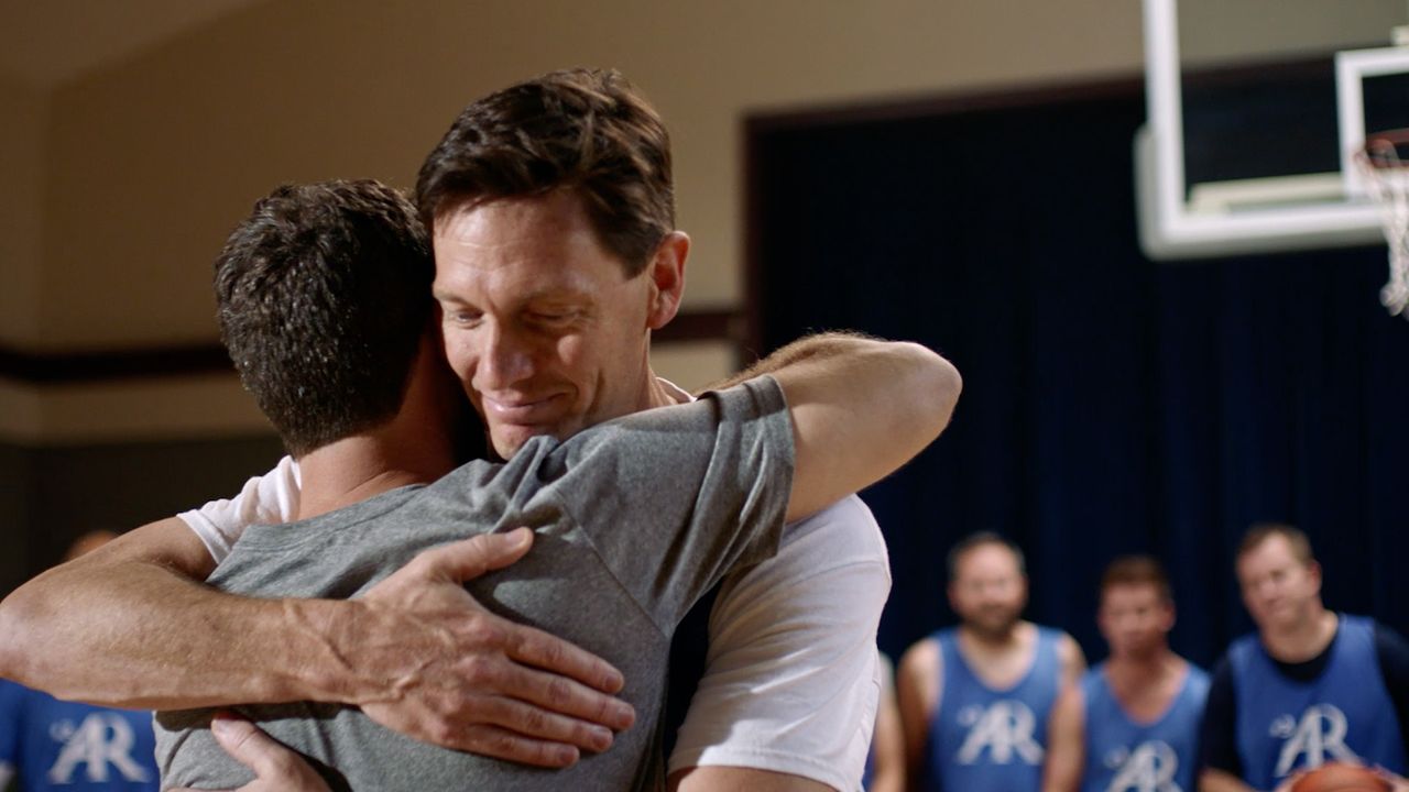 Dois amigos se abraçam numa quadra de basquete