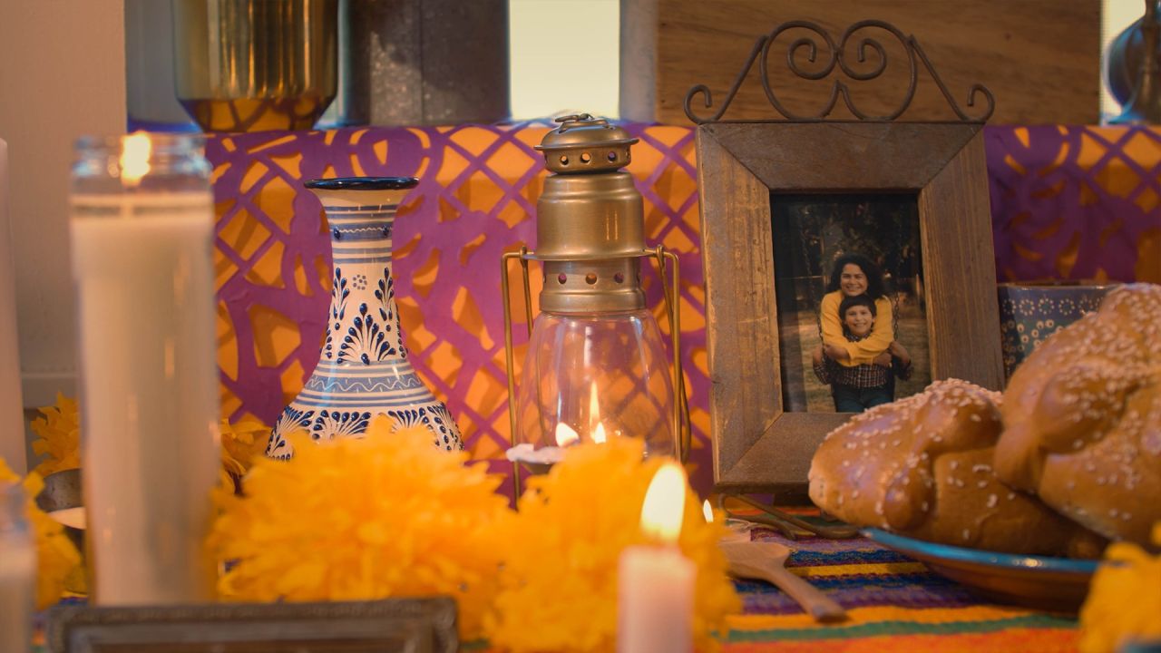 Un altar con fotos, candelas, y comida para el Día de los Muertos