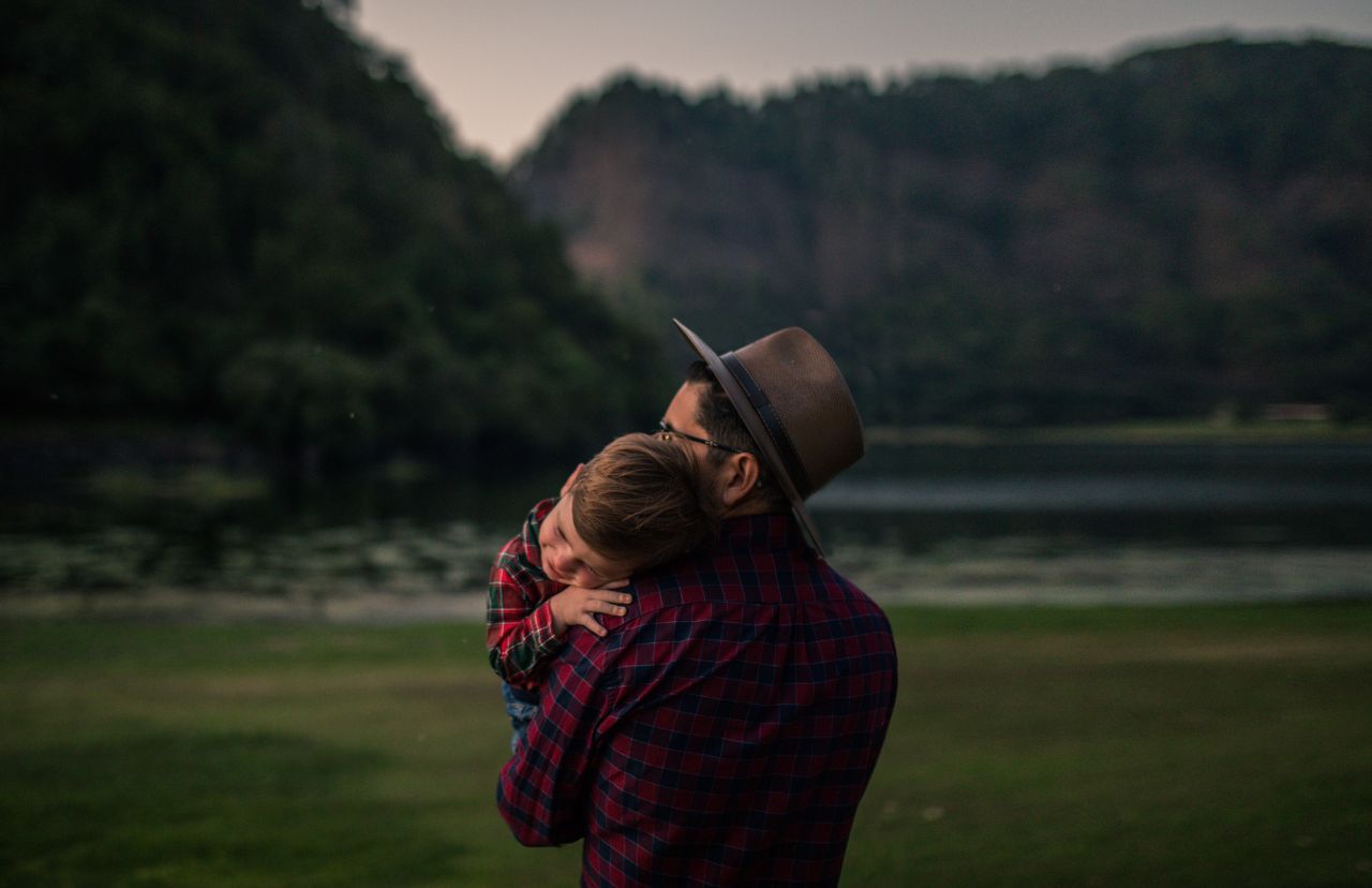 Un padre sostiene amorosamente a su hijo pequeño mientras disfrutan de la naturaleza