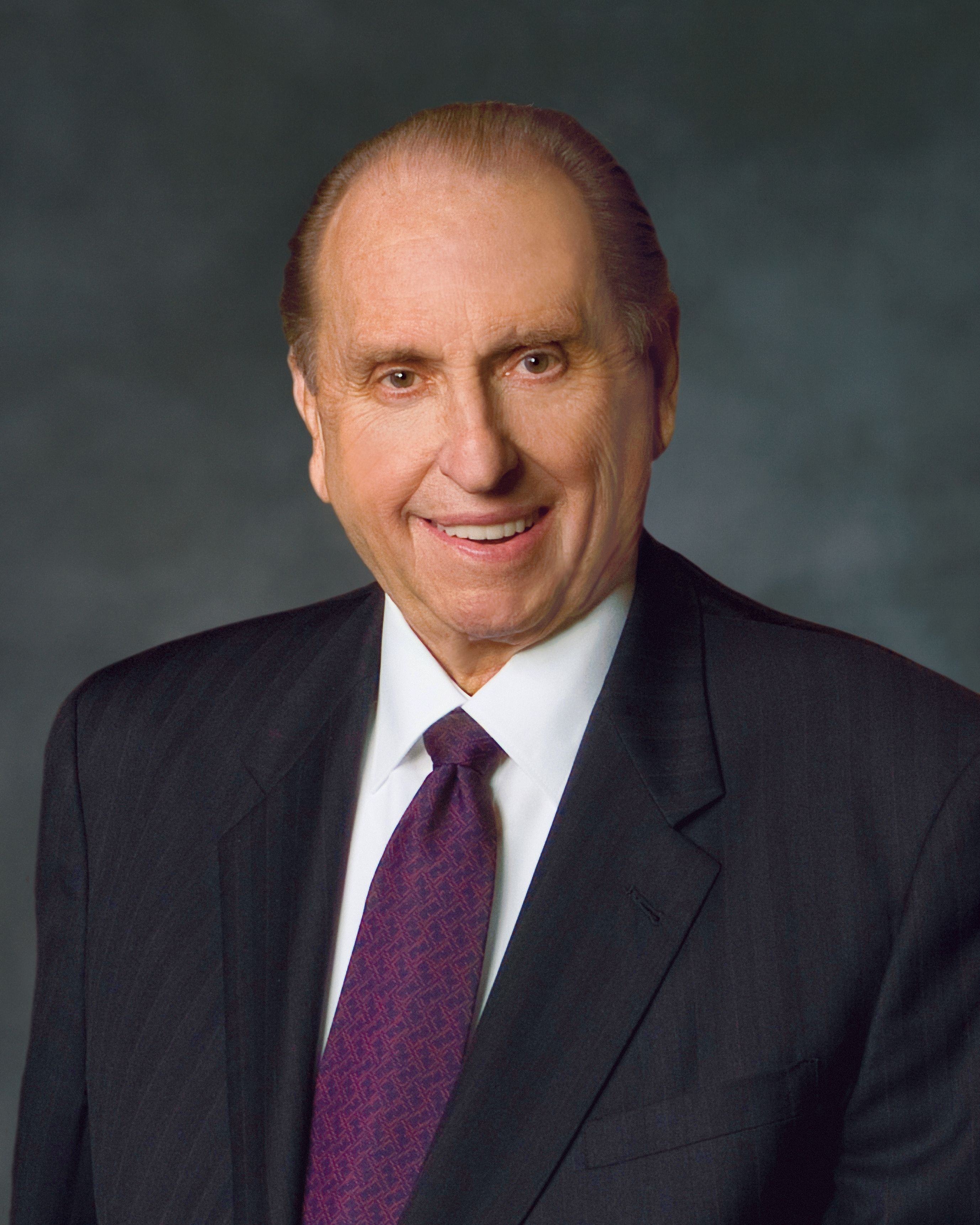 A formal portrait of President Thomas S. Monson, who is wearing a black suit and a purple tie, in front of a blue background.