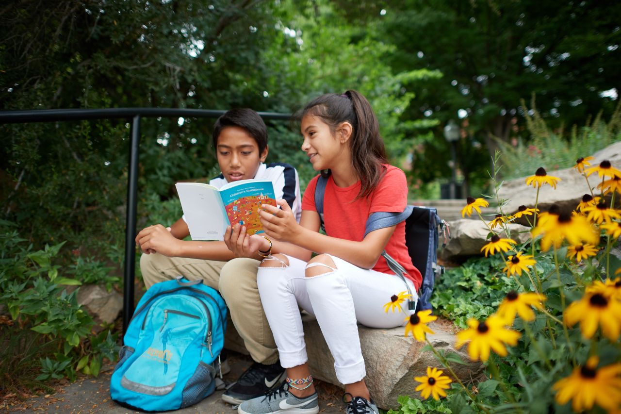 Young man and young woman reading booklet outside