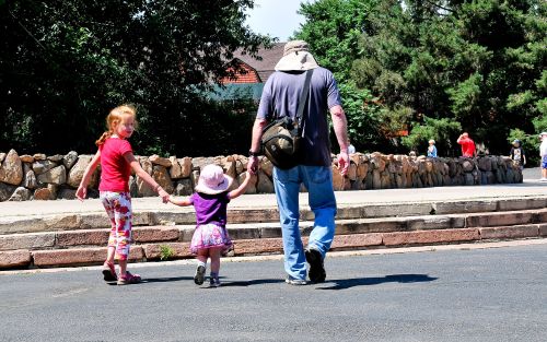 A man walking and holding hands with two girls.