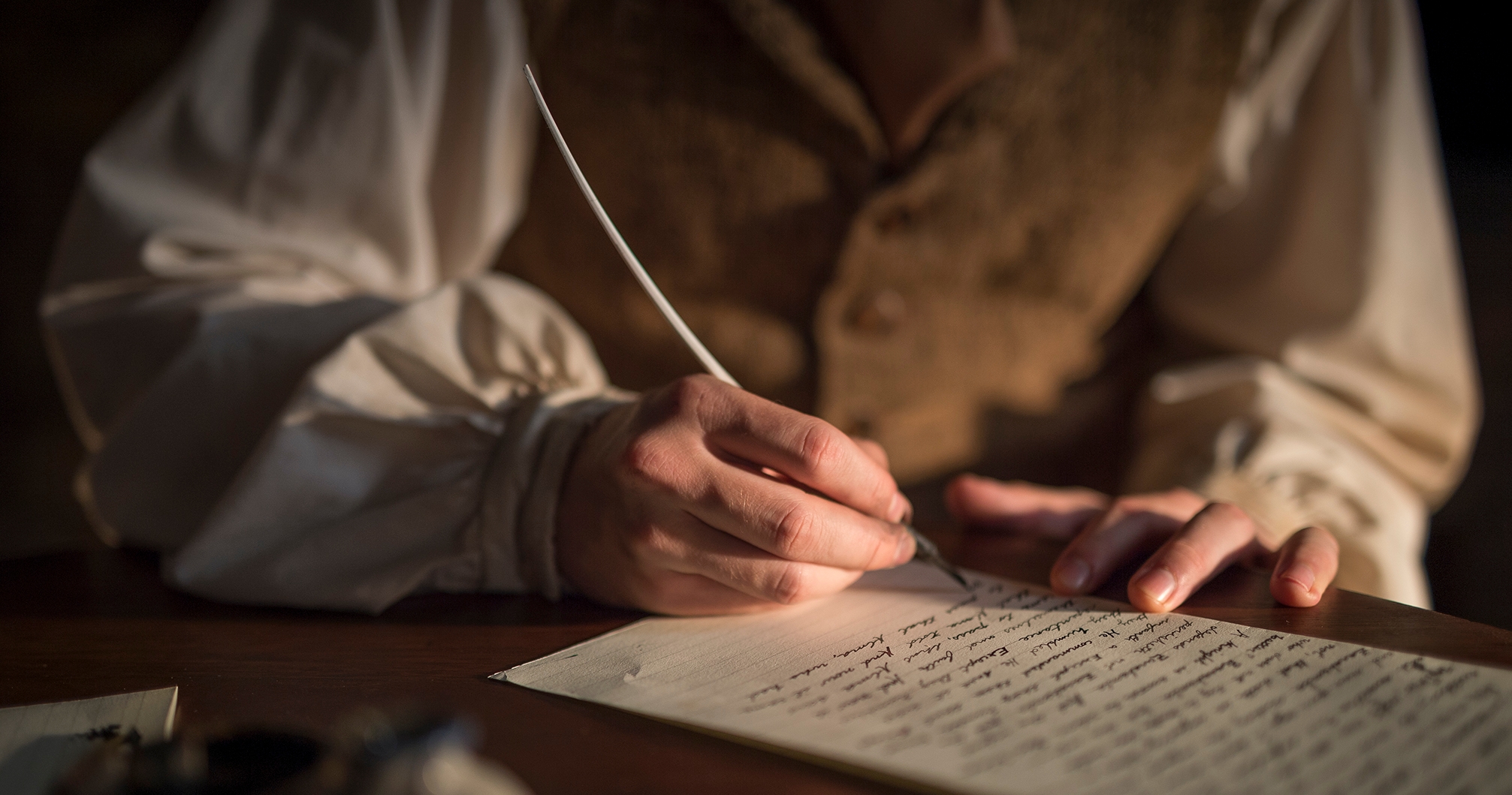 Image of Joseph Smith dictating a letter as scribe Oliver Cowdery writes with quil pen.