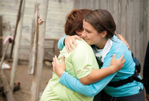 Emergency Response, Chile earthquake, youth and adult service projects, earthquake destruction.  A sister missionary embracing another woman.