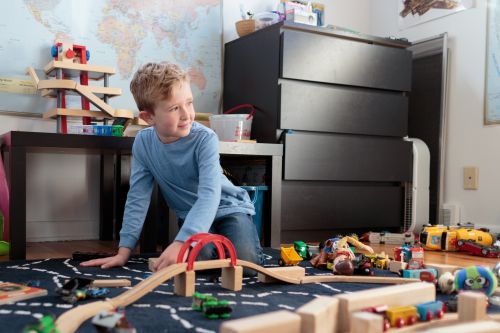 Boy surrounded by toys looking out of frame