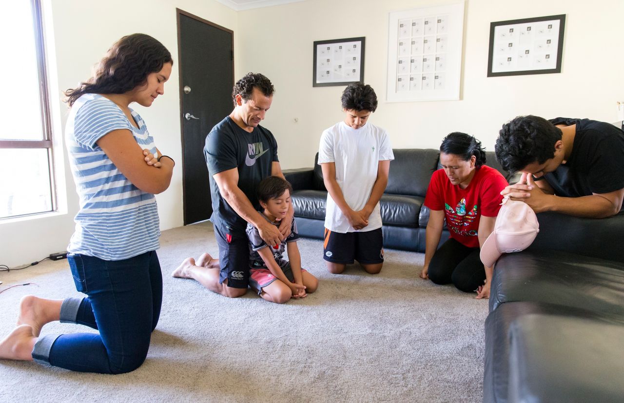 A couple and their children kneel together in family prayer